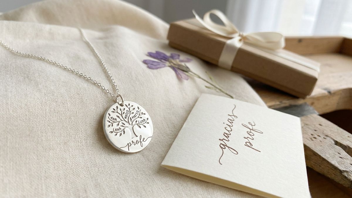 Colgante árbol de la vida de plata grabado para regalo profesora junto a una nota a mano que dice gracias profe