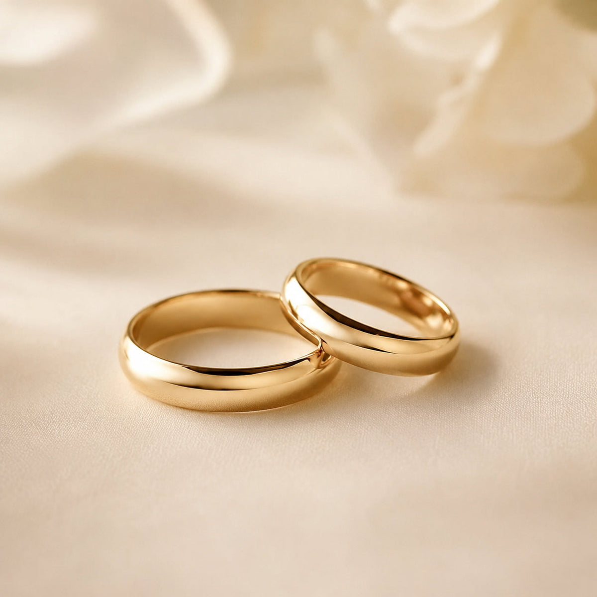Dos alianzas de boda de oro amarillo sobre tela de color crema