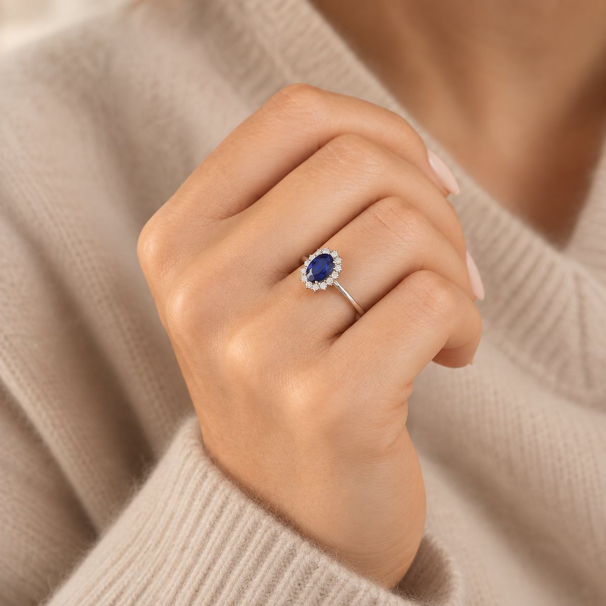 Anillo de zafiro azul con halo de diamantes en oro blanco puesto en la mano desde otro ángulo