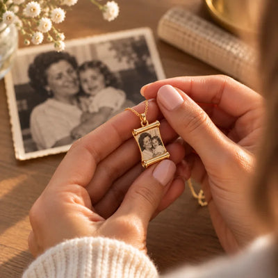 Manos sosteniendo un colgante portafotos de oro con la foto de un ser querido, junto a una fotografía antigua en blanco y negro