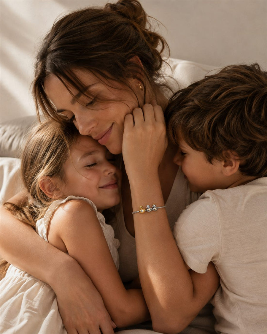 Madre abrazando a sus hijos con pulsera de patitos de plata